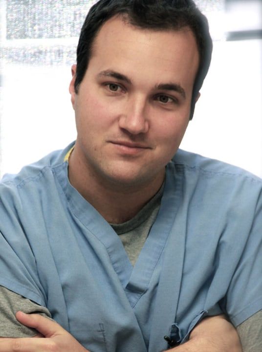 Dr. Beau J. Brasseale in blue scrubs, arms folded
