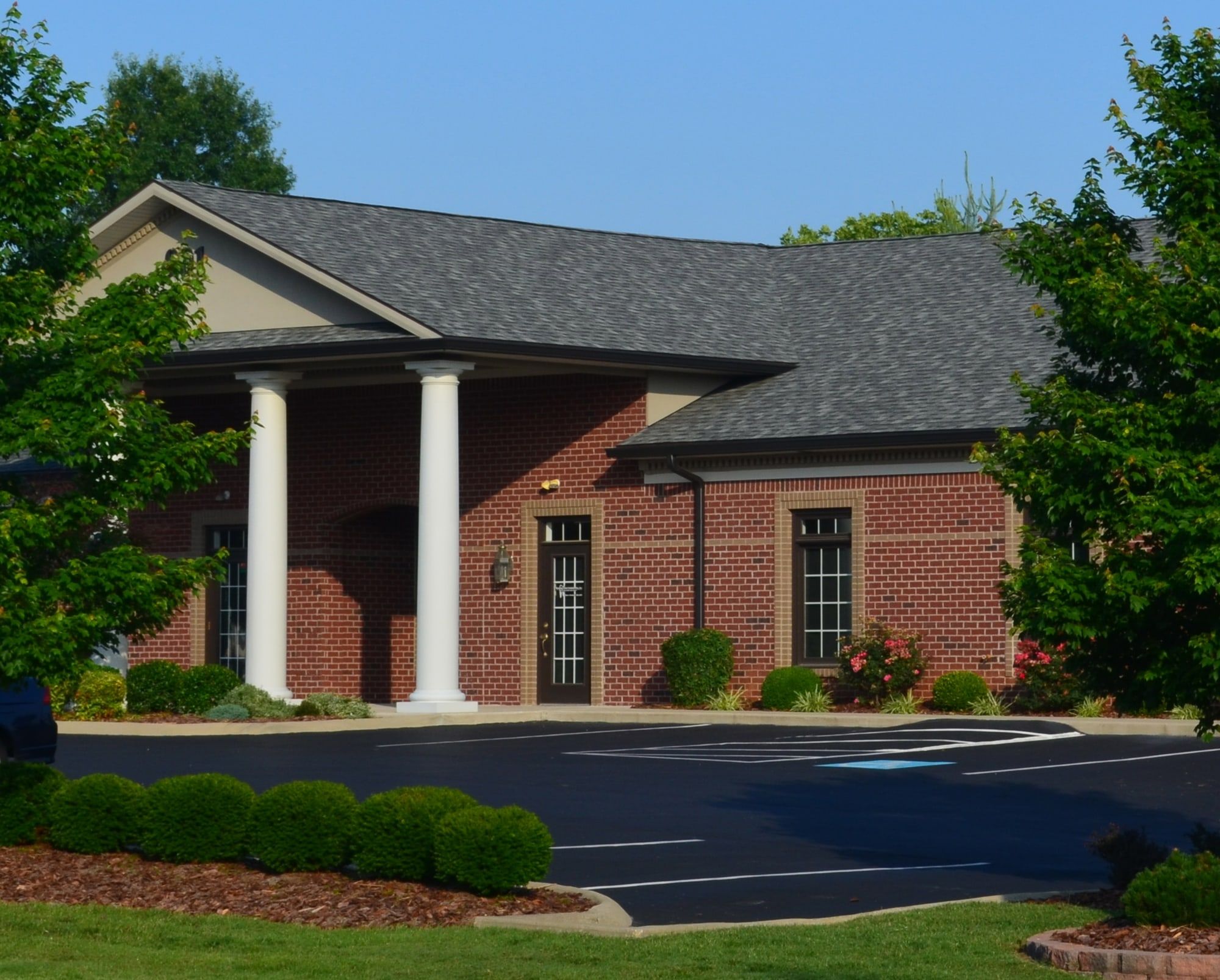 The front of the Bowling Green Endodontics building at 901 Wilkinson Trace: red brick, white columns and a lawn in summer