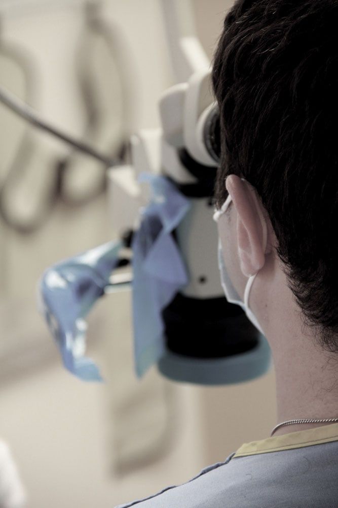 Over the shoulder of the endodontist looking through the surgical microscope