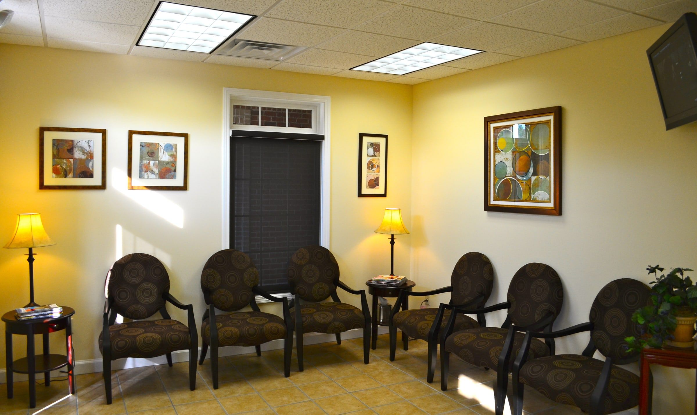 The waiting room: patterned armchairs, table lamps and framed art on warm yellow walls